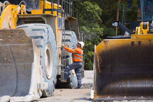 Man climbing up the payloader truck in a quarry. - Australian Stock Image