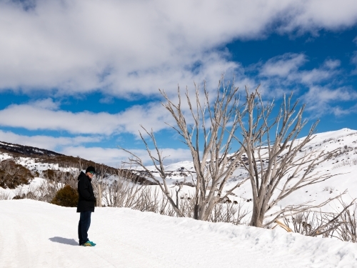 Man dressed in black, looking back in snow scene - Australian Stock Image