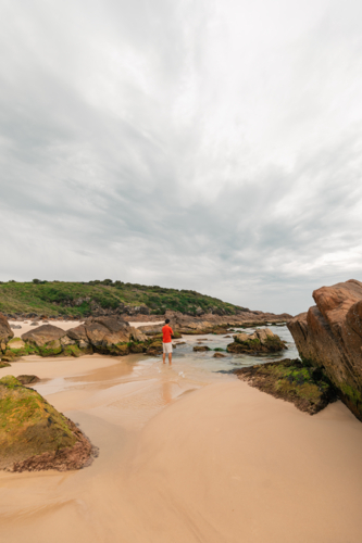 Man exploring rocky pools at Mungo Beach on the NSW coast - Australian Stock Image