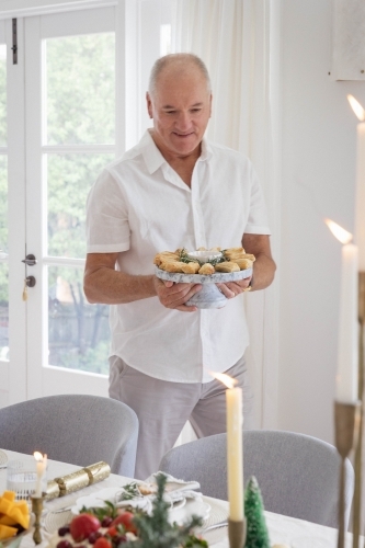 Man holding platter of pastries at Christmas table - Australian Stock Image