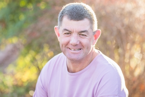 Man in 50s in garden smiling with dimples - Australian Stock Image