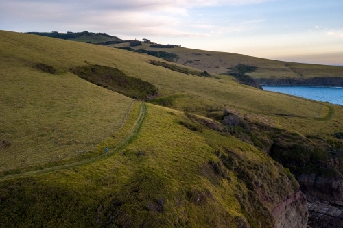 Man in Distance Running Along Cliff Edge - Australian Stock Image