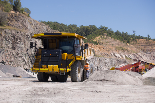 Man in high visibility clothes checking the sides of the dump truck. - Australian Stock Image