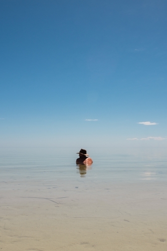 man in the ocean wearing akubra hat - Australian Stock Image