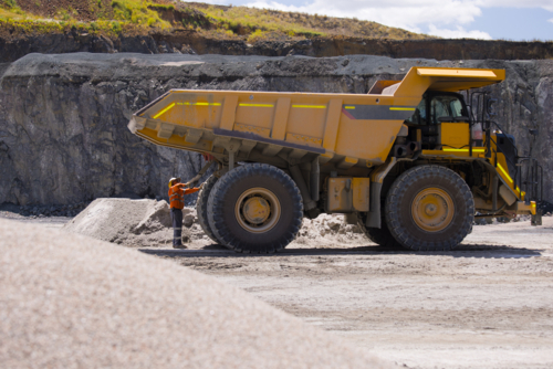 Man in workwear checking the back end of the hauler dump truck on mine site - Australian Stock Image