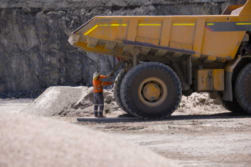 Man in workwear checking the back end of the hauler dump truck on mine site - Australian Stock Image