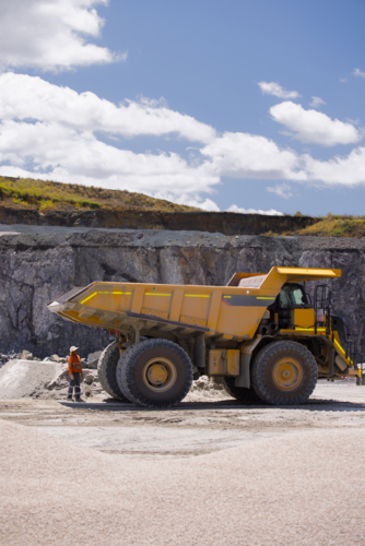 Man in workwear checking the back end of the hauler dump truck on mine site - Australian Stock Image