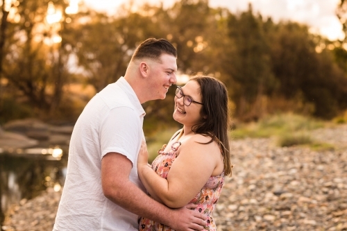 Man leaning in to whisper in partner's ear laughing - Australian Stock Image