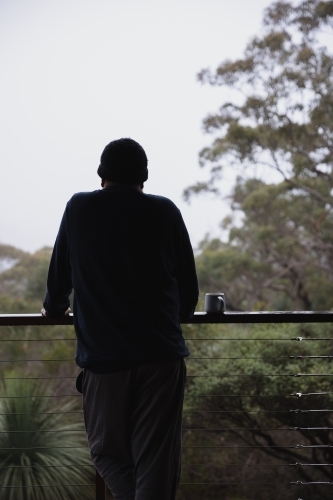 Man looking into the scrub from balcony - Australian Stock Image