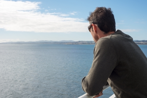 Man on cruise ship looking out to sea - Australian Stock Image