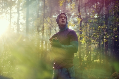 Man pausing in bushland on Morning Run in Fog and Sunshine - Australian Stock Image