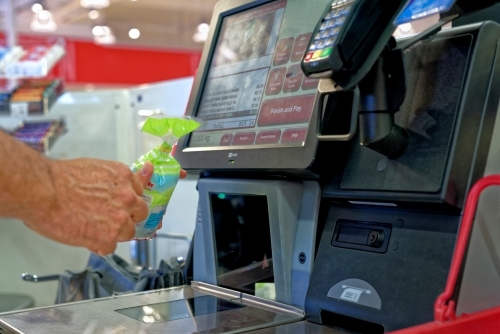 Man purchasing and scanning items at cash register - Australian Stock Image