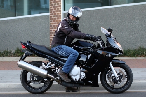 Man riding motorbike on a suburban street - Australian Stock Image