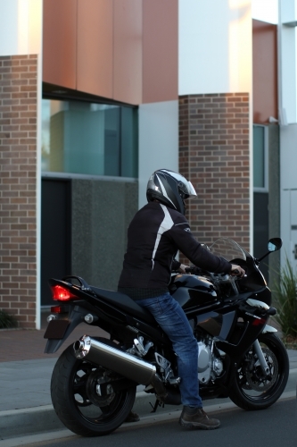 Man riding motorbike on a suburban street - Australian Stock Image