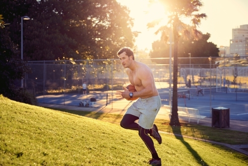 Man running up hill in the early morning with basketball - Australian Stock Image