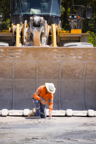 Man tightening the bolts on the bucket of a payloader. - Australian Stock Image