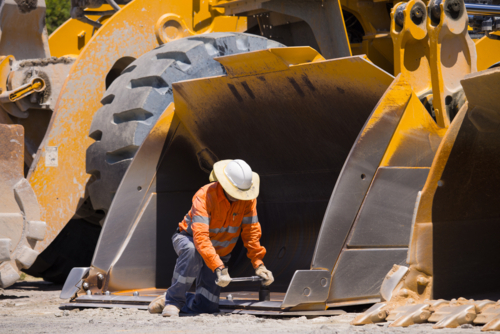 Man tightening the bolts on the bucket of a payloader. - Australian Stock Image