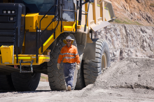 Man walking away from the dump truck with massive wheels. - Australian Stock Image