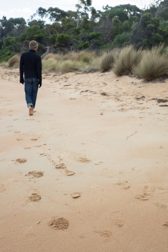 Man walking on beach on winter day - Australian Stock Image