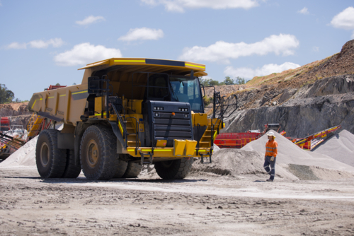 Man walking towards the dump truck with massive wheels. - Australian Stock Image