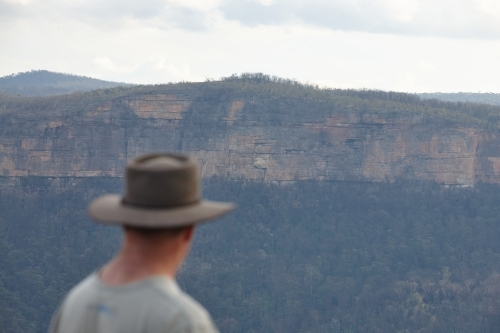 Man wearing Akubra hat looking out over mountain range - Australian Stock Image