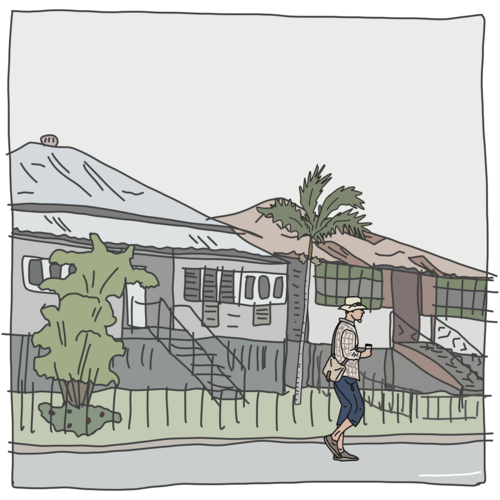 Man with take away coffee and cross body bag walking in a street lined with old houses on a grey day - Australian Stock Image