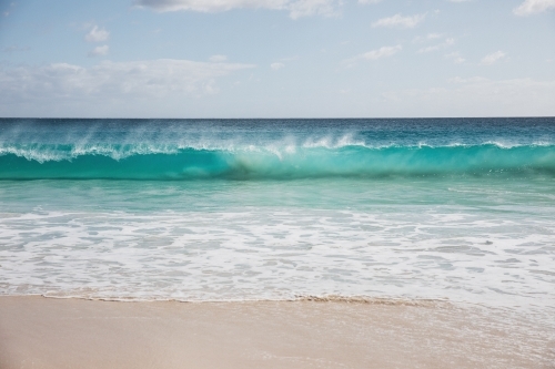 Mare's tail on waves breaking on beach - Australian Stock Image