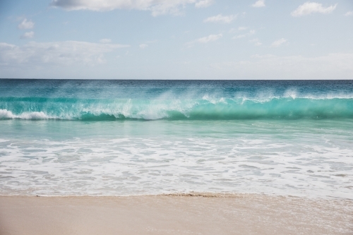 Mare's tail on waves breaking on beach - Australian Stock Image