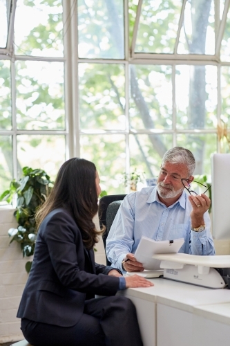 Mature aged male office worker meeting with a woman in a creative warehouse space - Australian Stock Image