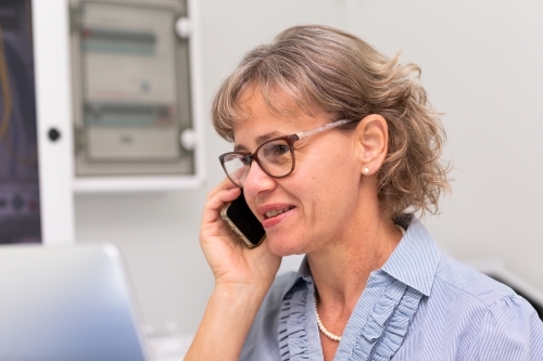Mature business woman holding phone to ear in office - Australian Stock Image