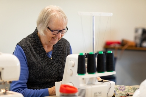 mature lady sewing with overlocking machine - Australian Stock Image