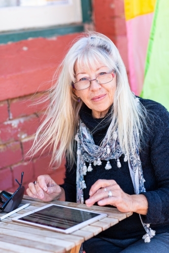 Mature lady wearing spectacles using tablet - Australian Stock Image