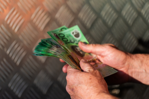 Middle aged man holding hundreds of dollars of Australian cash beside meal tool box on ute - Australian Stock Image