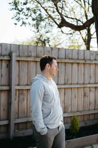 Middle-aged man standing in front of a wooden fence in the yard - Australian Stock Image