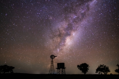 Milky Way setting behind a windmill and water tank on a clear night.