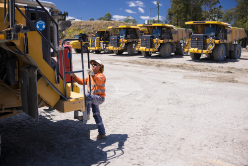Mining operator man holding on the handrails while climbing up the dump truck - Australian Stock Image