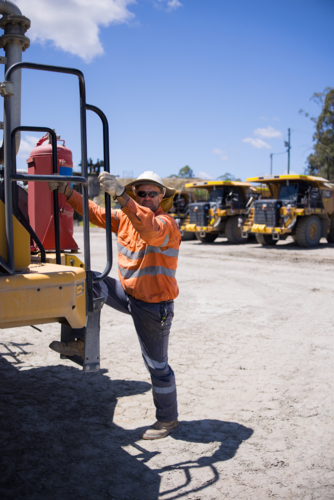 Mining operator man holding on the handrails while climbing up the dump truck - Australian Stock Image