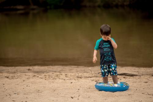 Mixed race 3 year old boy plays on a river bank with an inflatable swimming tube