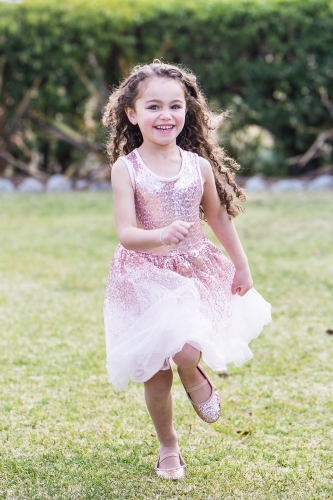 Mixed race aboriginal caucasian girl running laughing in garden - Australian Stock Image