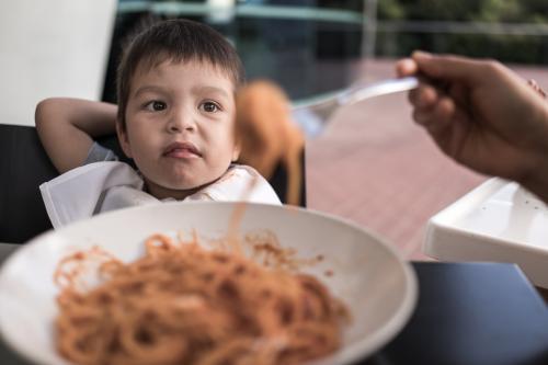 Mixed race boy eating pasta at a suburban Italian restaurant - Australian Stock Image