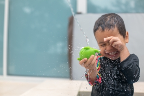 Mixed race boy playing in small backyard pool - Australian Stock Image