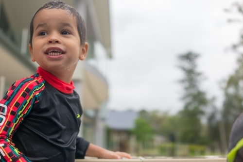 Mixed race boy playing in small backyard pool - Australian Stock Image