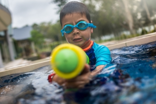 Mixed race boy playing in small backyard pool