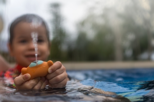 Mixed race boy playing in small backyard pool - Australian Stock Image