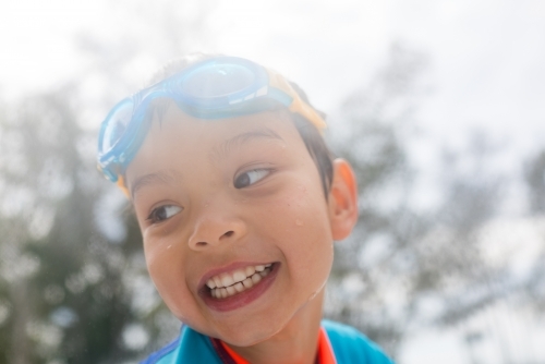 Mixed race boy playing in small backyard pool - Australian Stock Image