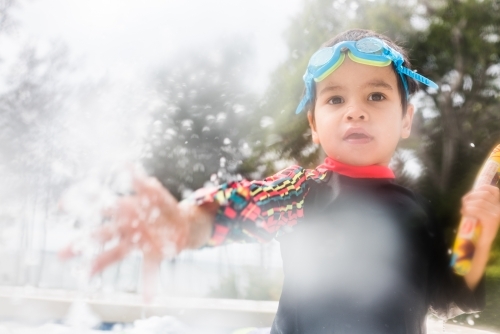 Mixed race boy playing in small backyard pool - Australian Stock Image