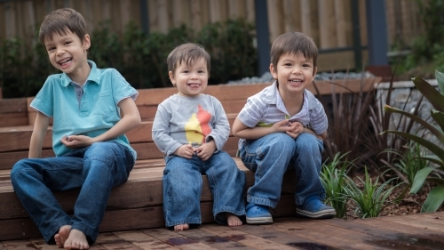 Mixed race brothers play together in their suburban backyard - Australian Stock Image