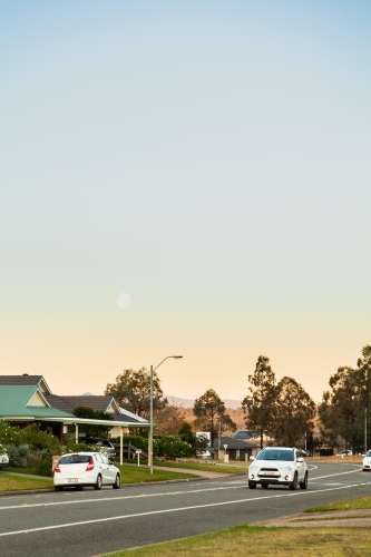 Moon in sky at dusk over suburban street in singleton - Australian Stock Image