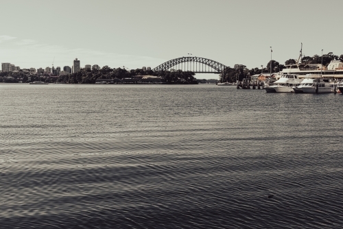 Monochromatic view of Sydney Harbour Bridge and cbd from afar, across the bay - Australian Stock Image