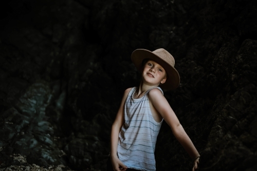 Moody image of young boy exploring dark cave in tropical north Queensland - Australian Stock Image